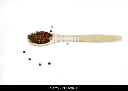 Grains de poivre rouge de près, dans une cuillère en bois sur fond blanc isolé Banque D'Images
