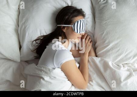 Vue de dessus paisible jeune femme portant un masque dormant sur le côté Banque D'Images