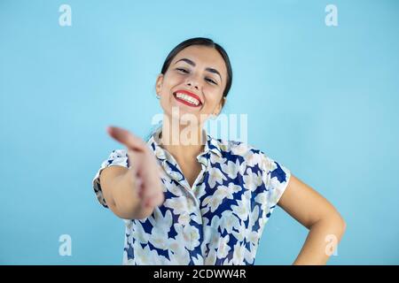 Jeune belle femme souriante amicale offrant poignée de main comme salutation et accueillante. Banque D'Images