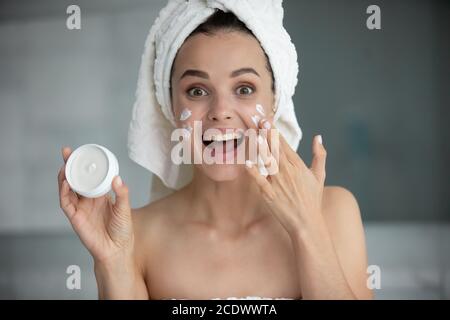 Tête portrait drôle jeune femme tenant le visage crème pot Banque D'Images