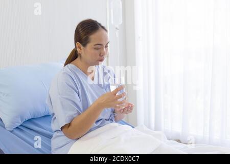 Femmes asiatiques assises sur un lit mangeant des médicaments l'hôpital Banque D'Images