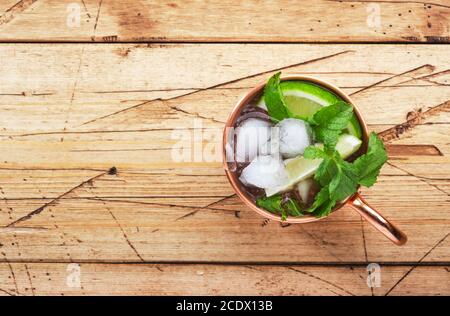 Cocktail moscovite mule en tasse de cuivre avec citron vert, bière au gingembre, vodka et menthe. Table en bois, vue de dessus, espace de copie Banque D'Images