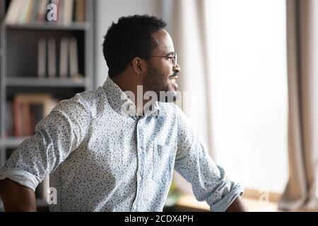 Homme afro-américain souriant et rêveur pensant à l'avenir ou aux opportunités Banque D'Images