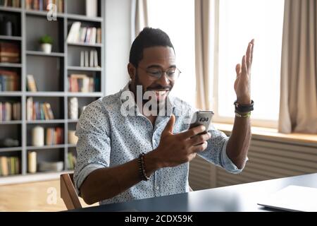 Heureux Africain américain homme excité par de bonnes nouvelles, en utilisant le téléphone Banque D'Images