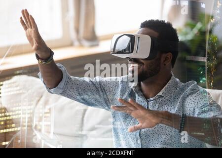 Homme afro-américain souriant en lunettes VR bénéficiant de la réalité augmentée Banque D'Images