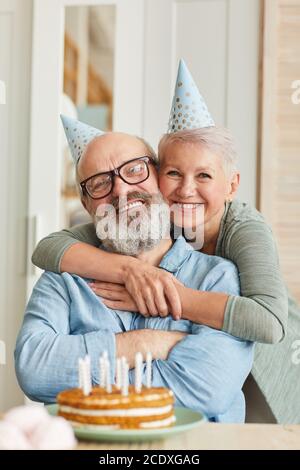 Portrait d'une famille de deux personnes âgées souriantes à l'appareil photo tout en étant assis à la table avec un gâteau et en célébrant l'anniversaire Banque D'Images