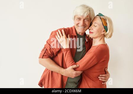 Couple affectueux mûr s'embrassant l'un l'autre sur fond blanc Banque D'Images