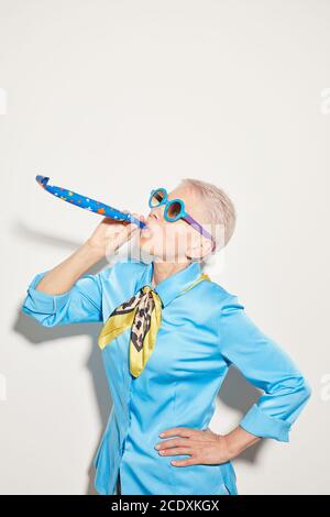 Femme âgée en lunettes de soleil s'amusant sur fond blanc Banque D'Images
