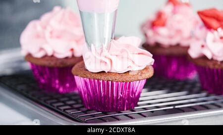 Vue rapprochée. Étape par étape. Piotage de crème de beurre italienne sur les cupcakes en velours rouge. Banque D'Images