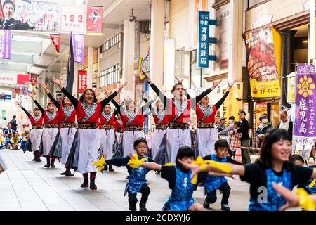 Équipe japonaise de femmes matures danseuses de yosakoi dansant avec de petits enfants en face dans la salle de shopping pendant le festival Kyusyu Gassai à Kumamoto. Banque D'Images