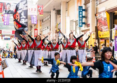 Équipe japonaise de femmes matures danseuses de yosakoi dansant avec de petits enfants en face dans la salle de shopping pendant le festival Kyusyu Gassai à Kumamoto. Banque D'Images