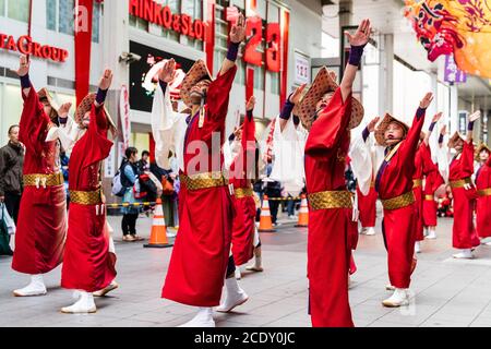 Équipe japonaise de danseurs de yosakoi portant des chapeaux de paille et des manteaux de happi rouges, dansant dans la galerie marchande de Sun Road, pendant le festival Kyusyu Gassai. Banque D'Images