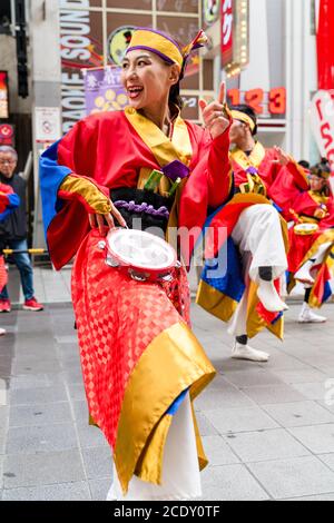 Gros plan d'une femme japonaise mûre, faisant partie d'une équipe de danse de yosakoi, dansant avec le tambourin pendant le festival Kyusyu Gassai à Kumamoto au Japon. Banque D'Images