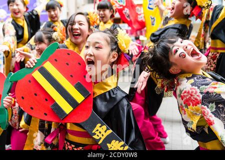 Deux jeunes danseuses japonaises Yosakoi, penchés en arrière avec des têtes ensemble chantant, l'une regardant directement le spectateur, pendant le festival Kyusyu Gassai. Banque D'Images