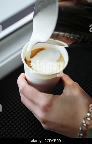 Le barista tire du lait sur un café, ce qui fait de l'art du Latte pour cappuccino Banque D'Images