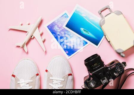 Jouet avion, appareil photo, chaussures et photos sur fond rose, vue de dessus Banque D'Images