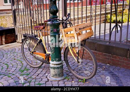 Un vélo avec un panier en bois dans une belle vieille rue avec des pavés dans la vieille ville de Düsseldorf. Banque D'Images