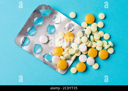 Différents comprimés, comprimés dans des emballages de plaquettes, médicaments médicaments sur fond bleu. Banque D'Images