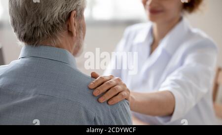 Gros plan femme médecin touchant l'épaule du patient senior, réconfortant Banque D'Images