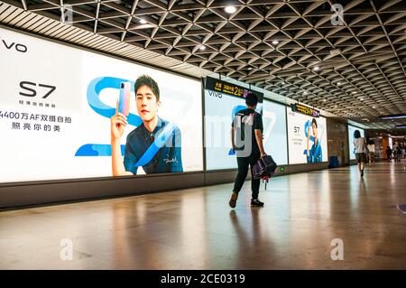 Les navetteurs parcourent une large publicité pour le téléphone mobile Vivo S7 tout en passant de la ligne 2 à la ligne 10 de la gare routière de Nanjing est à Shanghai. Banque D'Images