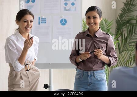Deux collègues de race mixte heureux présentant les résultats des études de marketing. Banque D'Images