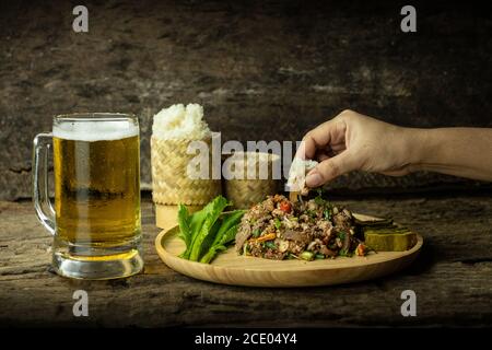 porc, épicé, émincé, gluant, riz, collant, bière, manger, salade, verre, larme, main, tenir, femme, traditionnel, thaï, nourriture, larme moo, nord-est, mi épicé Banque D'Images