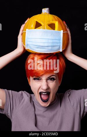 crier fille avec citrouille avec masque facial - halloween dedans l'âge du coronavirus Banque D'Images