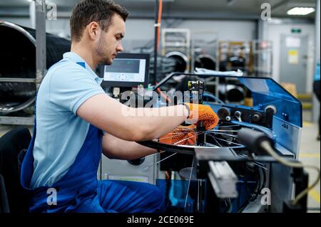 Un employé avec une machine-outil installe des rayons de vélo Banque D'Images