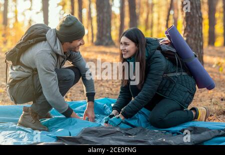 Un jeune homme et une jeune femme qui font la tente ensemble, ayant la conversation Banque D'Images