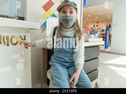 Une petite fille portant un masque médical de protection dans un centre commercial pendant une quarantaine de coronavirus. Banque D'Images