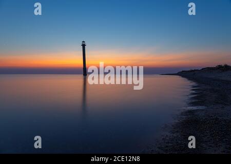 Phare de Kiipsaare à Saarema, Estonie. Site emblématique de la région - le phare abandonné est en biais. Coucher de soleil avec un ciel rouge. Banque D'Images