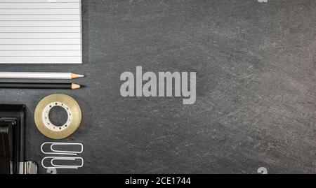 Arrière-plan en ardoise avec des supllies d'école noires et blanches. Banque D'Images