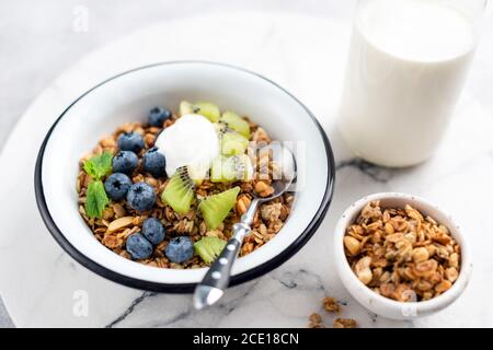 Granola avec fruits et yaourt dans un bol sur fond de table en marbre. Nourriture durable, concept de manger propre Banque D'Images