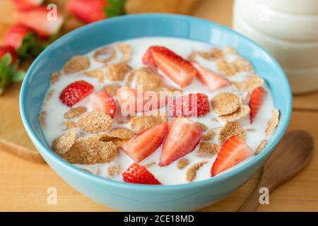 Flocons de grains entiers avec son de blé, fraises et lait d'amande dans un bol bleu pour un petit déjeuner sain Banque D'Images