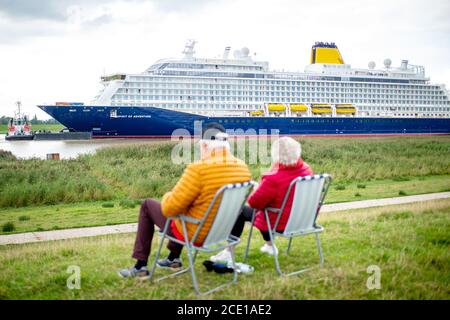 Westoverledingen, Allemagne. 30 août 2020. Un couple s'assoit sur deux chaises sur la digue près du village de Dorenburg et regarde le nouveau paquebot de croisière 'Spirit of Adventure', qui a quitté le chantier de Meyer et navigue sur l'EMS. Le navire construit pour la compagnie maritime britannique Saga Cruises doit être transféré à la mer du Nord par l'EMS. Credit: Hauke-Christian Dittrich/dpa/Alay Live News Banque D'Images