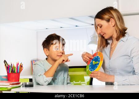 Enfant avec le trouble du spectre de l'autisme apprendre l'horloge et les heures, enseignant pendant la classe de thérapie d'ABA Banque D'Images