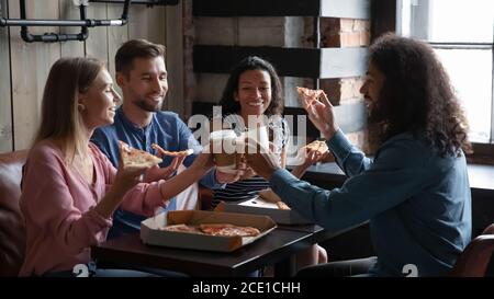 Des amis heureux et variés qui mangent de la pizza et s'amusent au café Banque D'Images