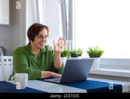 Portrait d'une femme âgée ayant une conversation en ligne à l'intérieur de la maison - dire Bonjour. Banque D'Images
