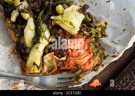 Saumon méditerranéen en papier parchemin : filet de saumon recouvert de cœurs d'artichaut, tomates séchées, câpres, olives kalamata, sauce au pesto et aneth Banque D'Images