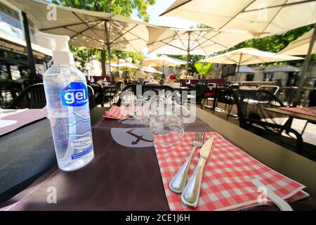 Table de restaurant française avec gel désinfectant antiCovid, alcoolique à côté des couverts. Banque D'Images