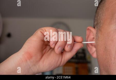 un homme nettoie ses oreilles avec un coton-tige Banque D'Images