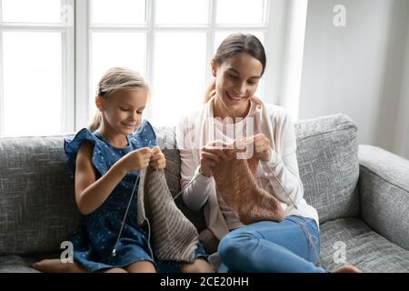 Bonne petite fille enfant impliquée dans le tricotage avec maman. Banque D'Images