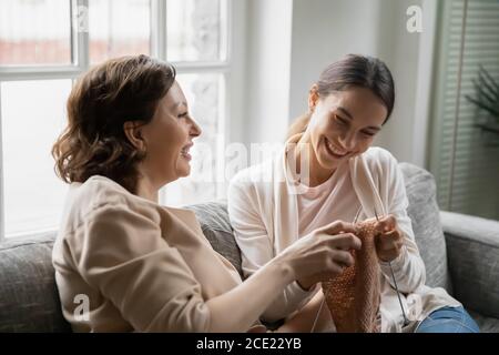 Heureuse femme d'âge moyen des années 60 enseignant fille de taille tricotage. Banque D'Images