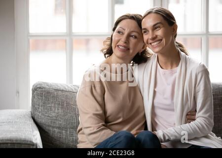 Rêveuse liant différentes générations de femmes mixte race famille se détendre à l'intérieur. Banque D'Images