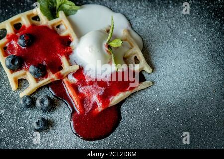 Gaufres belges classiques maison fraîches, parées de glace, de bleuets frais et de menthe, vue de dessus. Gaufres savoureuses. Concept petit déjeuner Banque D'Images