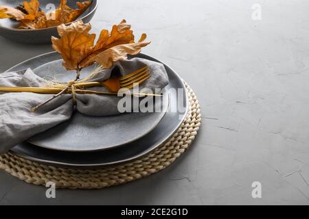Cadre élégant avec feuilles de chêne d'automne et couverts dorés sur fond gris. Gros plan. Banque D'Images