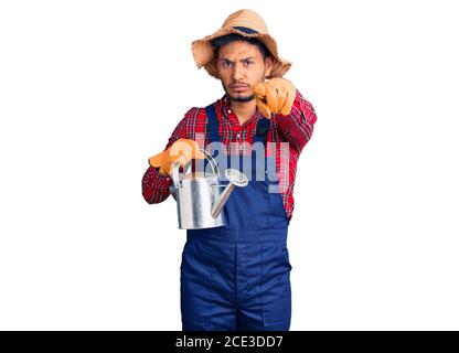 Beau jeune homme latino-américain tenant un téléphone vintage pointant avec le doigt vers l'appareil photo et vers vous, geste confiant regardant sérieux Banque D'Images