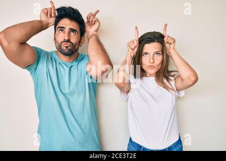 Beau jeune couple de petit ami et petite amie faisant ensemble drôle faites un geste avec le doigt sur la tête comme des cornes de taureau Banque D'Images