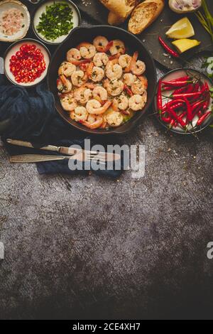 Crevettes grillées dans une poêle en fonte avec citron frais, persil, piment et sauce au vin blanc à l'ail Banque D'Images