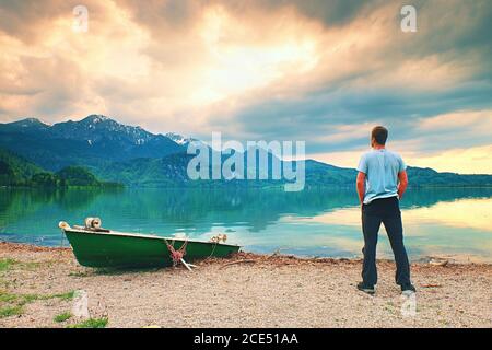 Adulte homme en chemise bleue promenade à bord d'un vieux bateau de pêche à aubes sur les montagnes de la côte du lac. Banque D'Images